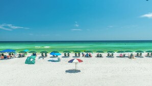 A beach with rows of umbrellas and beach chairs, a clear blue sky, and the ocean in the background. - DOTG 505 is a gorgeous 2 BR Gulf Front within a small complex to beat the crowds (Destin)