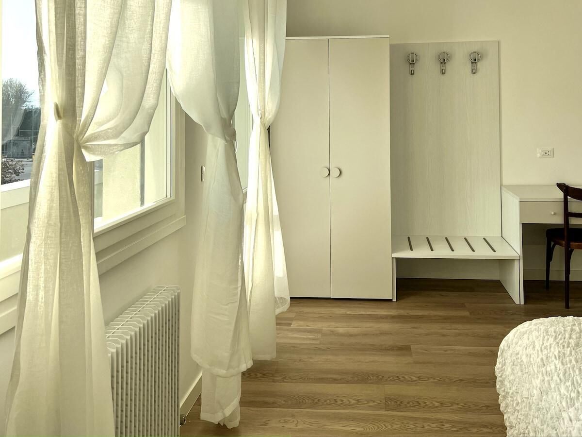 A bedroom with a large wardrobe, a radiator, a desk, and a chair.