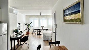 A modern living room with a dining area, a kitchen, and a large window with curtains.