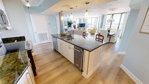 A modern kitchen with a central island, built-in appliances, and a dining area with a view. - East Pass Towers 304 is a Stunning 3 bedroom with Pass Views and recent upgrades (Destin)