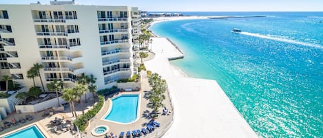 A resort with a large pool, a beach, and a view of the ocean.