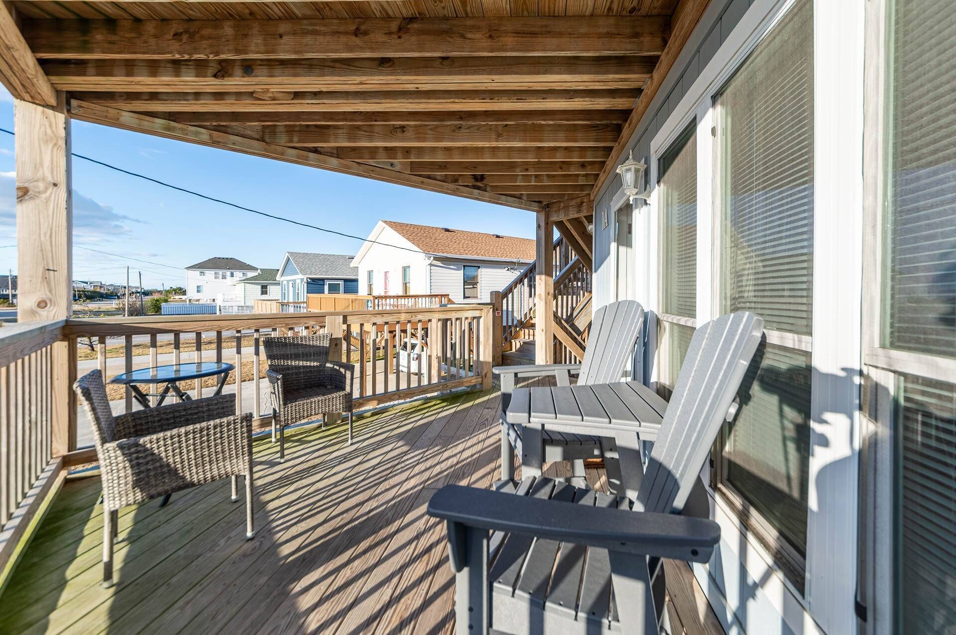 A covered porch with outdoor seating, a wooden deck, and a view of neighboring houses.