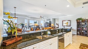 A spacious kitchen with a granite countertop, white cabinetry, and a large island with a sink.