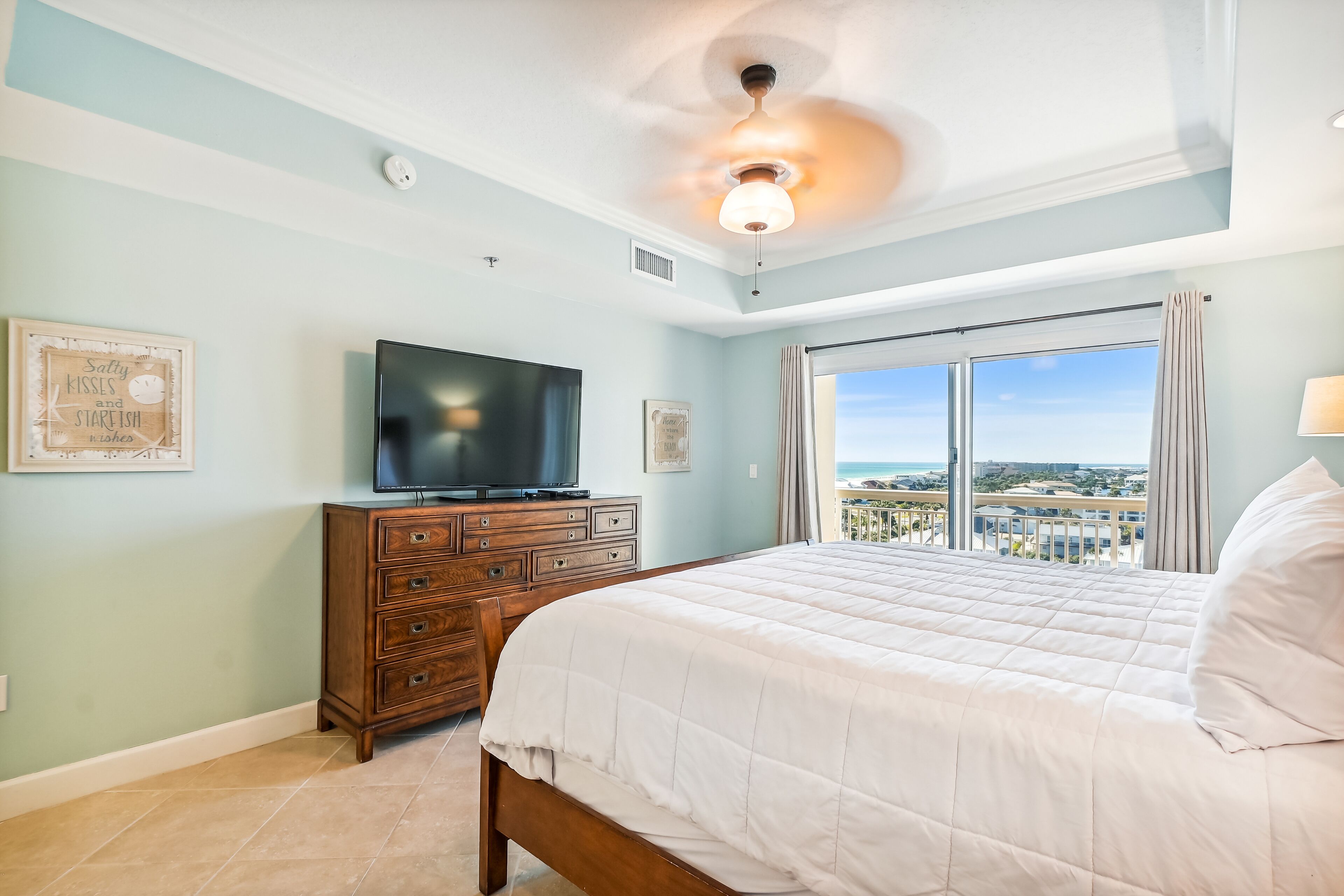 Ein Schlafzimmer mit Bett, Fernseher, Kommode und Blick auf die Stadt.
