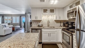 A modern kitchen with white cabinets, stainless steel appliances, and a granite countertop. - HSR 402 is a Luxury 2 BR - Completely Renovated and stunning in its decor (Destin)