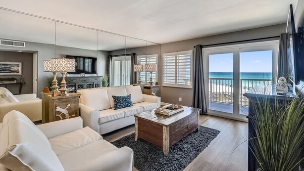 A living room with a sofa, coffee table, and a view of the beach through large windows. - HSR 402 is a Luxury 2 BR - Completely Renovated and stunning in its decor (Destin)