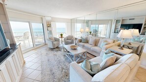 Ein geräumiges Wohnzimmer mit einem großen Sofa, einem Couchtisch und Meerblick durch große Fenster.