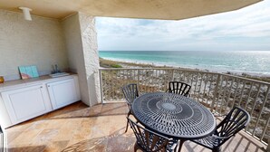 A balcony with a table and chairs, a sink, and a view of the ocean.