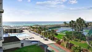 Une piscine d’hôtel avec vue sur l’océan, des espaces de détente en plein air et des courts de tennis.