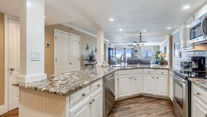 A spacious kitchen with white cabinetry, granite countertops, and stainless steel appliances. - IR 303 is a fully Renovated 2 BR Gulf Front with amazing views - Washer/Dryer (Destin)