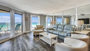 A spacious living room with a view of the ocean, a leather sofa, a coffee table, and a balcony with a chair. - Gorgeous Gulf front 2 BR completely remodeled with amazing gulf views - sleeps 7 (Destin)