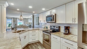 A modern kitchen with white cabinets, stainless steel appliances, and a marble countertop. - Gorgeous Gulf front 2 BR completely remodeled with amazing gulf views - sleeps 7 (Destin)