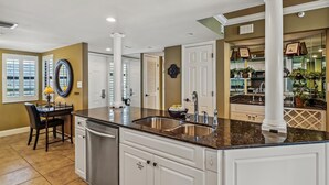 A kitchen with a central island, white cabinetry, stainless steel appliances, and a backsplash.