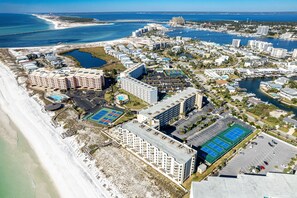 Luftaufnahme eines Küstenresorts mit mehreren Gebäuden, einem Strand und einer Marina.