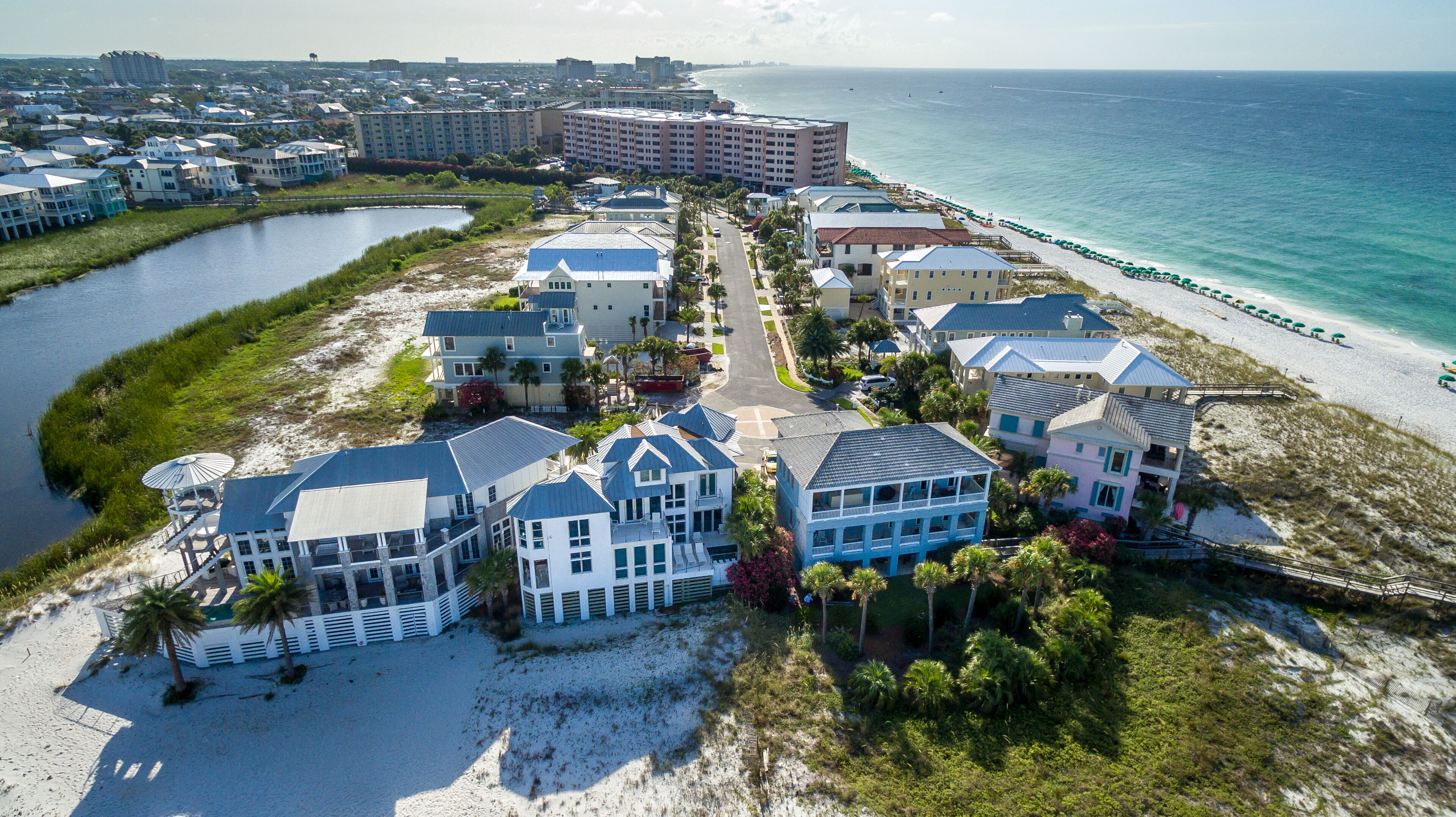 A coastal residential area with beachfront properties, a marina, and a beach with umbrellas.