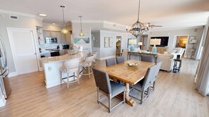 Una cocina amplia con una isla central, electrodomésticos modernos y un comedor con mesa y sillas de madera.