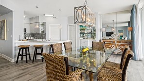 A modern kitchen with white cabinets, a central island, and bar stools.