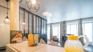 Ein Hotel-Rezeptionsbereich mit modernem Design, inklusive einer Rezeption, einer großen gelben Vase und einem Buch mit dem Titel 'Dans Ma Cuisine' auf der Theke.