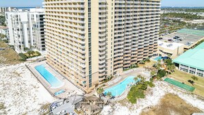 Un hotel de gran altura con varios balcones, una zona de piscina y vistas a la playa.