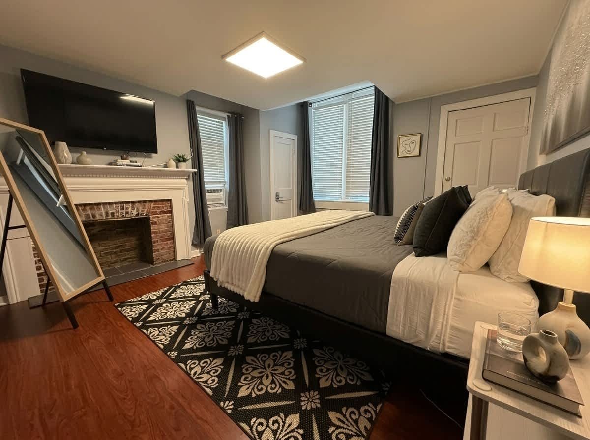 Un dormitorio con una cama, televisión, chimenea y ventana con persianas.