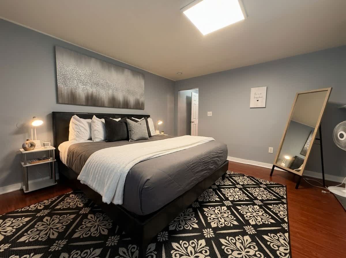 Ein Schlafzimmer mit einem Bett, Nachttischen, einem Spiegel und einem gemusterten Teppich.