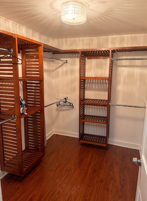 A walk-in closet with wooden shelving and a ceiling light fixture. - Spacious Historic King Suite (Wilmington)