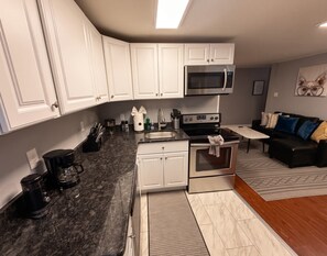 A modern kitchen with white cabinets, a microwave, stove, and coffee maker. - Spacious Historic King Suite (Wilmington)