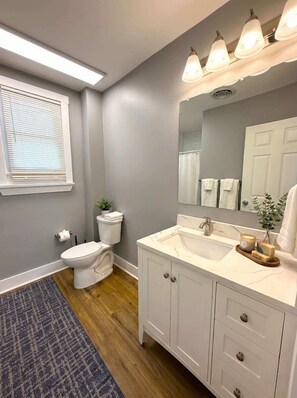 Een badkamer met toilet, wastafel, spiegel en een raam met zonwering.