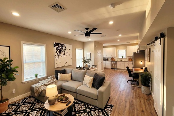 Open living area with sofa seating, coffee table, ceiling fan, and view toward the kitchen.