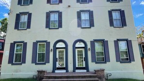 A two-story building with a symmetrical facade, numbered doors, and a central entrance with steps. - Modern Loft with Skyline Views - King & Queen Beds, Close to Downtown! (Wilmington)