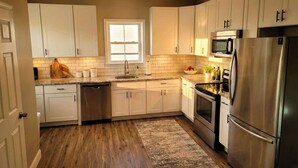 A modern kitchen with white cabinets, a stainless steel refrigerator, a microwave, and a dishwasher. - Modern Loft with Skyline Views - King & Queen Beds, Close to Downtown! (Wilmington)