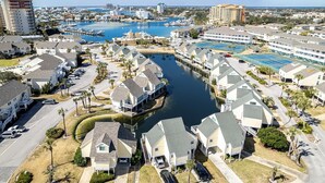 Un quartier résidentiel en bord de mer, avec des maisons, un port de plaisance et un grand hôtel doté de plusieurs piscines.