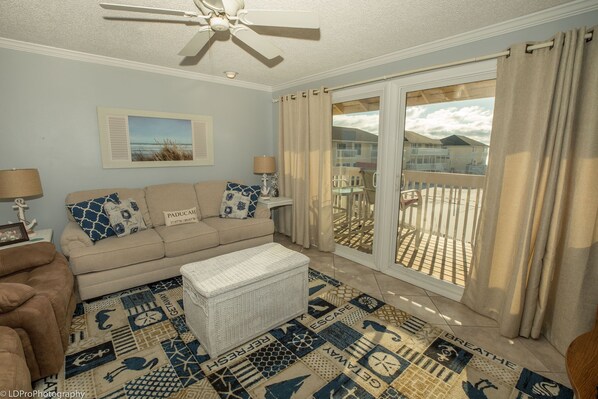 A living room with a beige sofa, a white ottoman, and a patterned rug. - SPC 2119 - Beautiful 2nd Floor 1 BR - sleeps 4 (Destin)