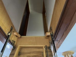 Un plafond en bois avec des poutres apparentes et une ouverture centrale.