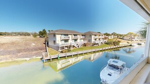 A multi-story building with balconies, a dock, and a boat.