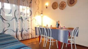 A room with a bed, a dining table with chairs, a lamp, and decorative plates on the wall. - Adorable Gardened 650m From the Beach (San Michele al Tagliamento)