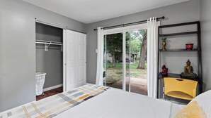 Une chambre à coucher comprenant un lit, une armoire, une chaise et une étagère ornée d’objets décoratifs.