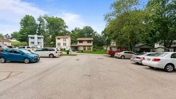 Un parking avec plusieurs voitures et des maisons en arrière-plan.