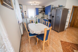 Eine kleine Küche mit Esstisch, Stühlen und einem Kühlschrank.