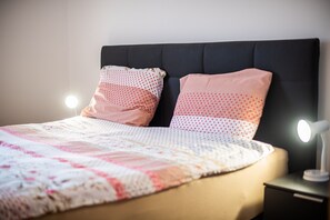 Ein Bett mit einer Decke, zwei Kissen und einer Nachttischlampe.