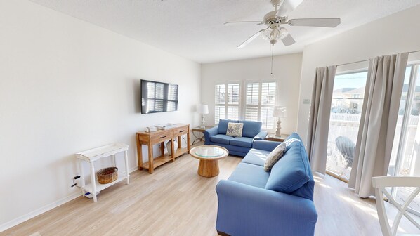 A spacious living room with a blue sofa, a wooden coffee table, and a ceiling fan. - SPC 9206- Gorgeous 1 BR - sleeps 6 (Destin)