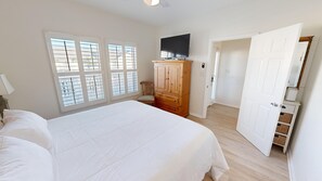 A bedroom with a large bed, a wooden wardrobe, a television, and a door leading to another room. - SPC 9206- Gorgeous 1 BR - sleeps 6 (Destin)