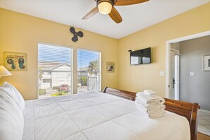 A hotel room with a large bed, a ceiling fan, a TV, and a view of the outside through the window. - SPC 9210 - Upstairs 1 BR sleeps 6 washer/dryer (Destin)