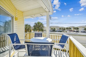 A balcony with a table and chairs, overlooking a street with palm trees and buildings. - SPC 9210 - Upstairs 1 BR sleeps 6 washer/dryer (Destin)