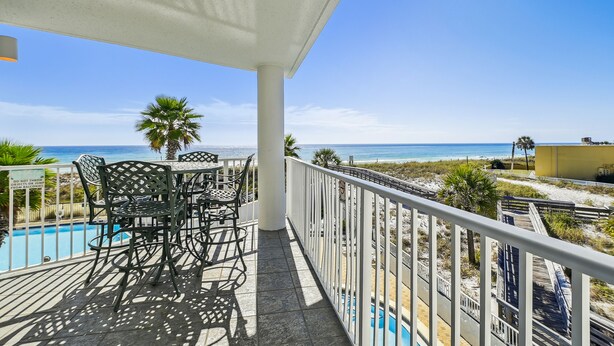 Un balcon avec piscine, un espace salon extérieur et une vue sur la plage et l’océan.
