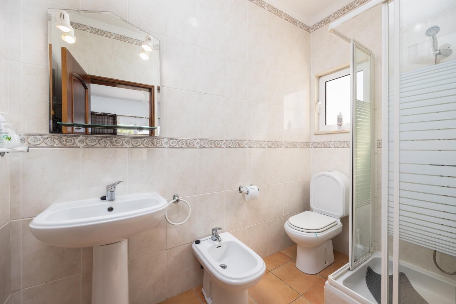 A bathroom with a sink, bidet, toilet, and shower.