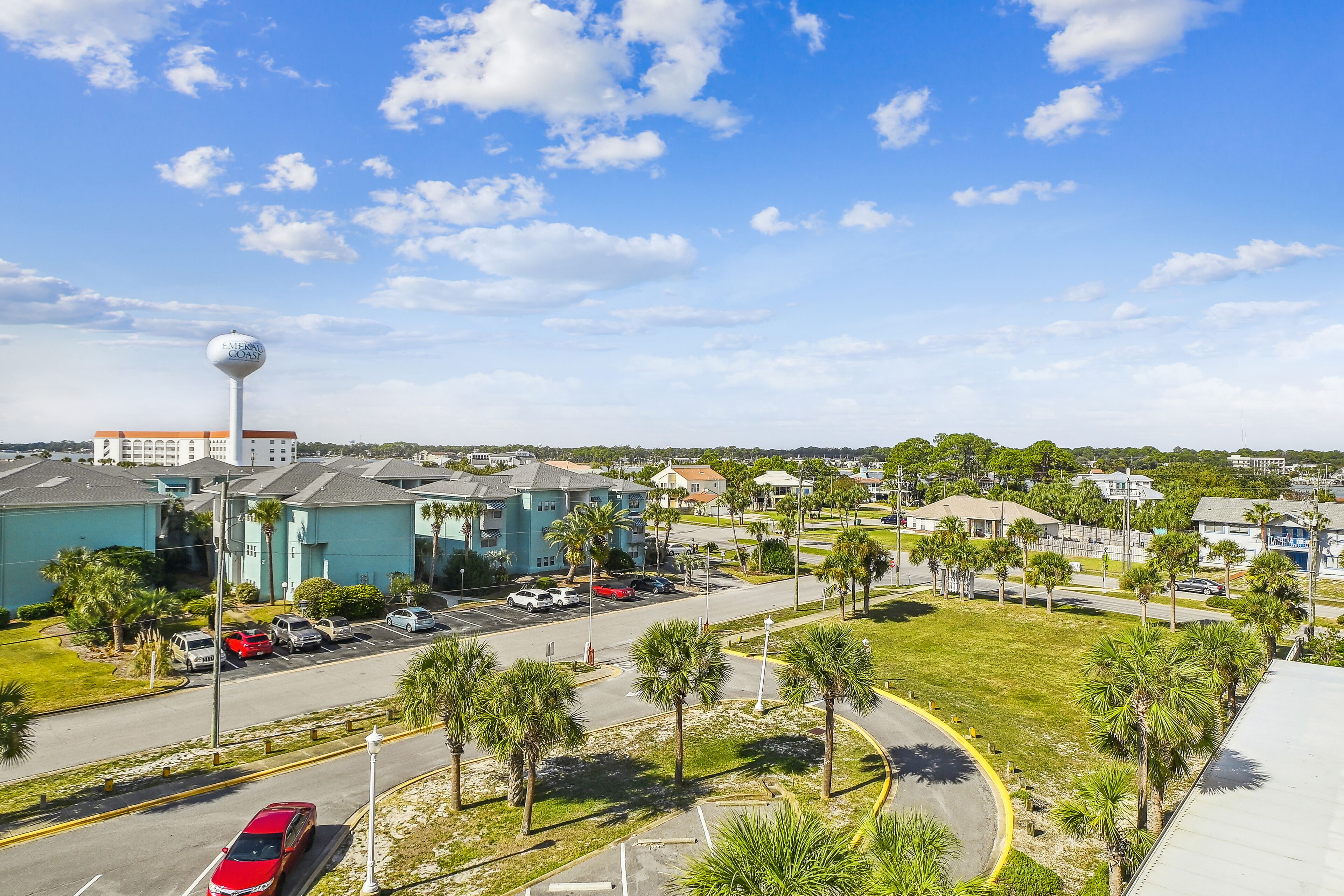 A parking lot with several cars, a building with a sign, and a clear blue sky.