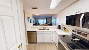 Une cuisine moderne avec des meubles blancs, un lave-vaisselle, une cuisinière et un four à micro-ondes.