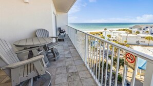Un balcon avec une table et des chaises, donnant sur une plage où il est interdit de fumer.
