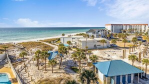 Un hôtel situé en bord de mer, doté d’une piscine, d’un accès direct à la plage et d’un grand bâtiment comportant de nombreux balcons.
